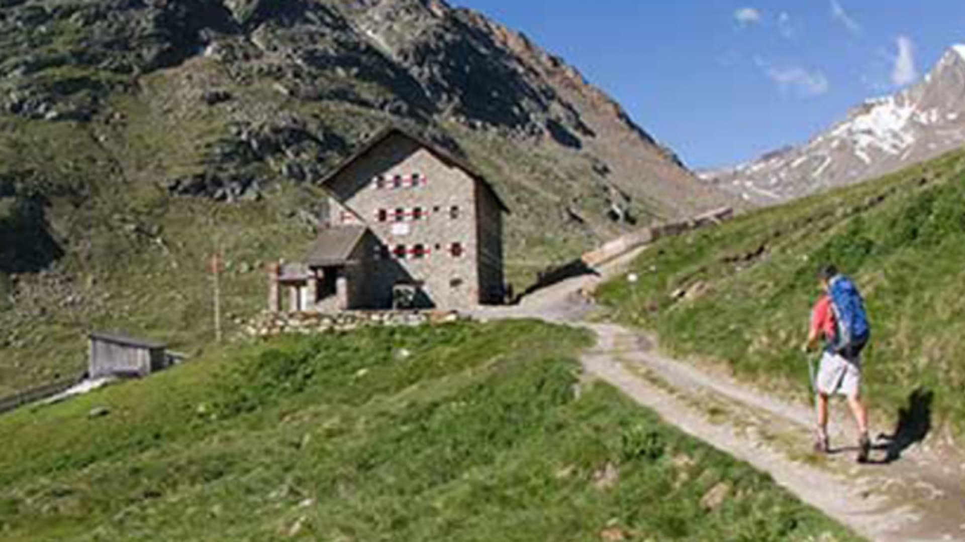 Bergwanderer auf dem Zustieg zur Martin-Busch-Hütte in den Ötztaler Alpen mit schneebedeckten Gipfeln im Hintergrund.