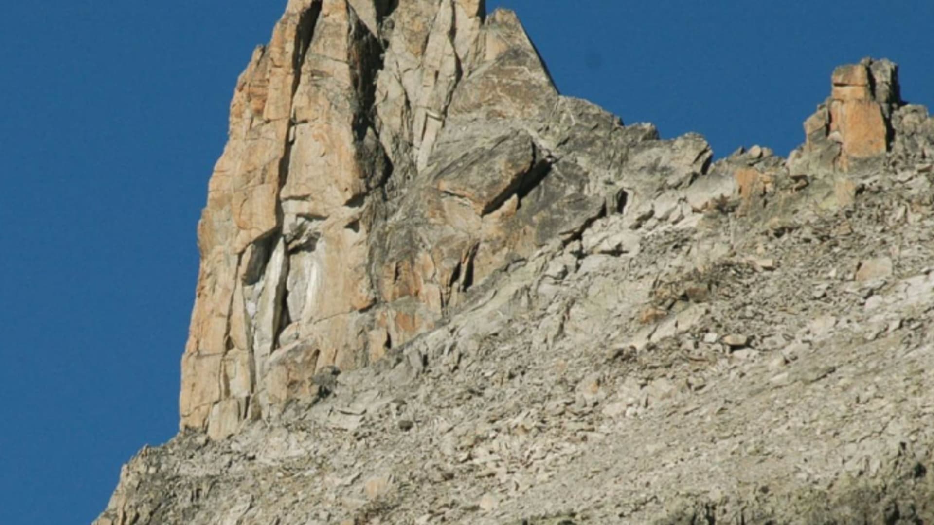 Die Cabane d'Orny steht vor einer steilen Felswand aus hellem Gestein in alpiner Landschaft.