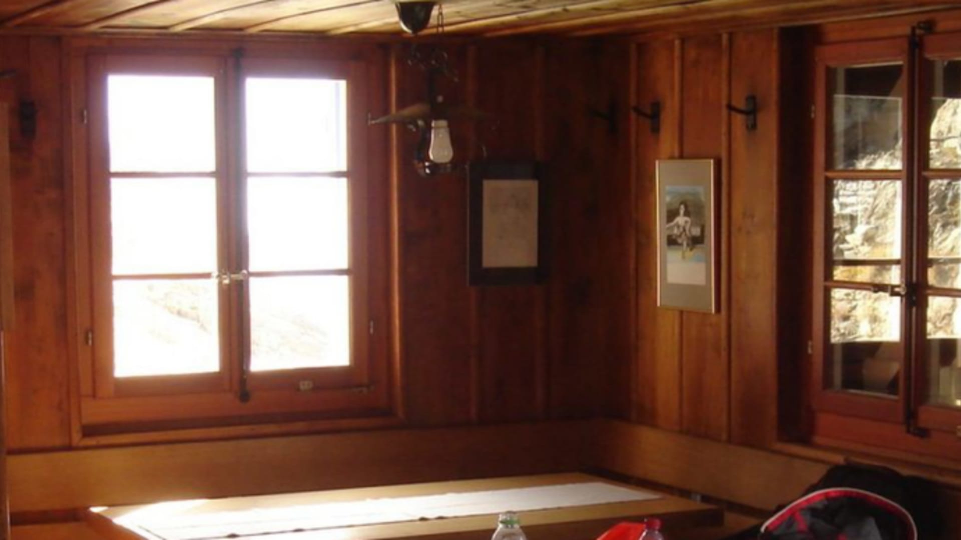 Gastraum der Chelenalphütte mit Holztisch, Sitzbank und traditioneller Holzverkleidung an den Wänden.