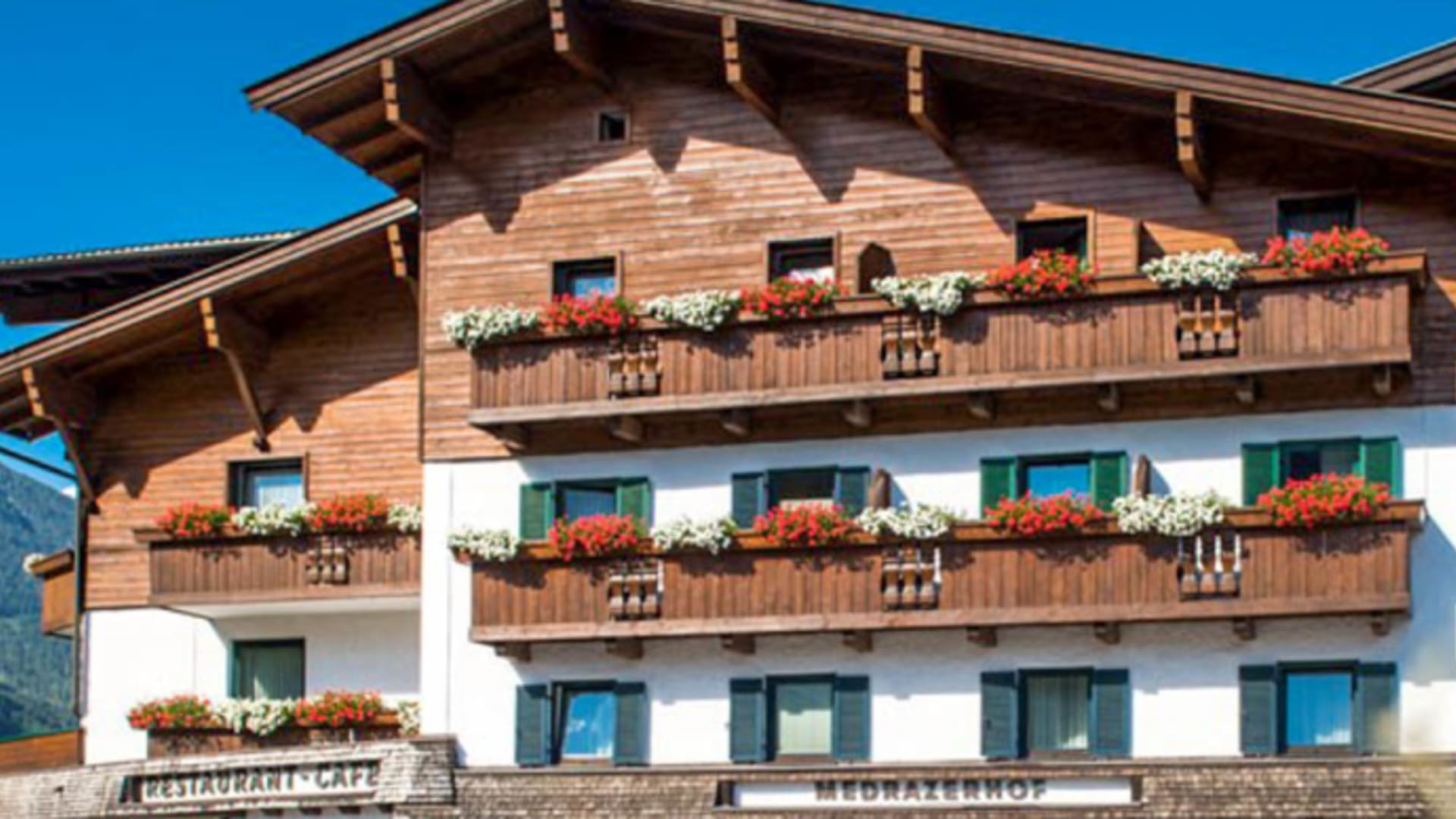 Das Hotel Medrazerhof präsentiert sich als traditionelles alpines Gebäude mit Holzbalkonen und Blumenschmuck in Fulpmes.