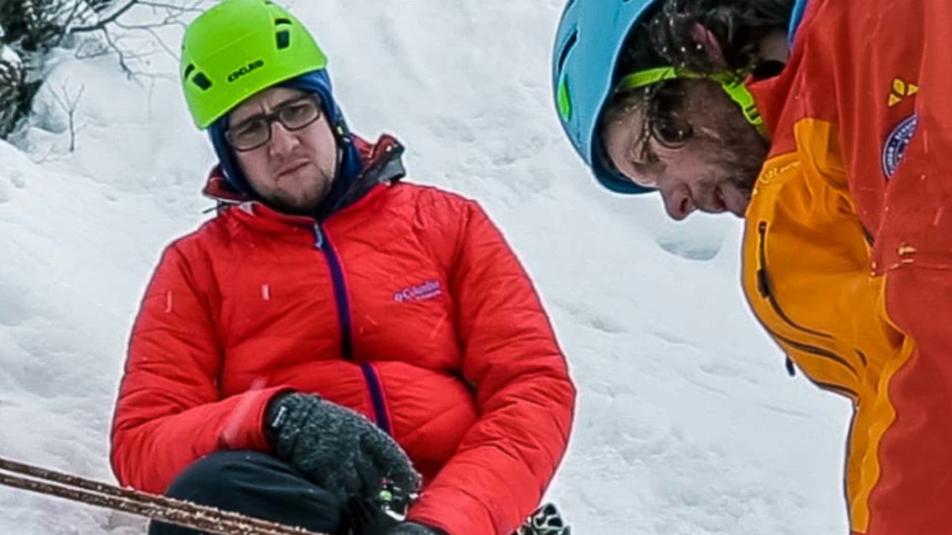 Eisklettern: Abseilen beim Eiskletterkurs – Bergführer demonstriert Sicherungstechnik mit Sicherungsgerät und Eispickel-Anker