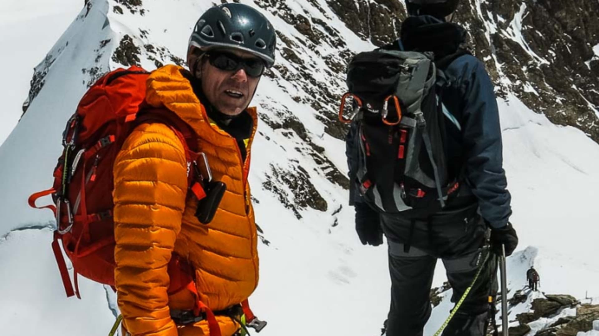 Hochtour am Mönch: zwei Bergsteiger im Seil auf einem schneebedeckten Fels-Grat im Abstieg.