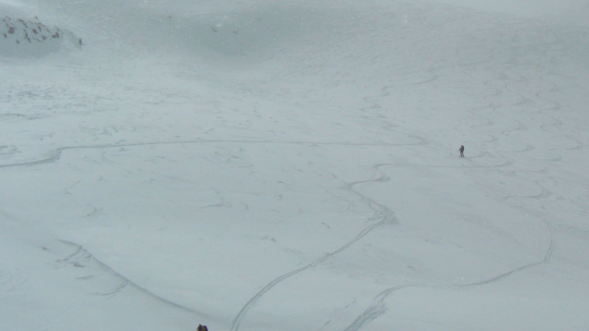 Skitourengeher bei der Abfahrt zur Sesvennahütte im Vinschgau auf einem verschneiten Hang bei Nebel.