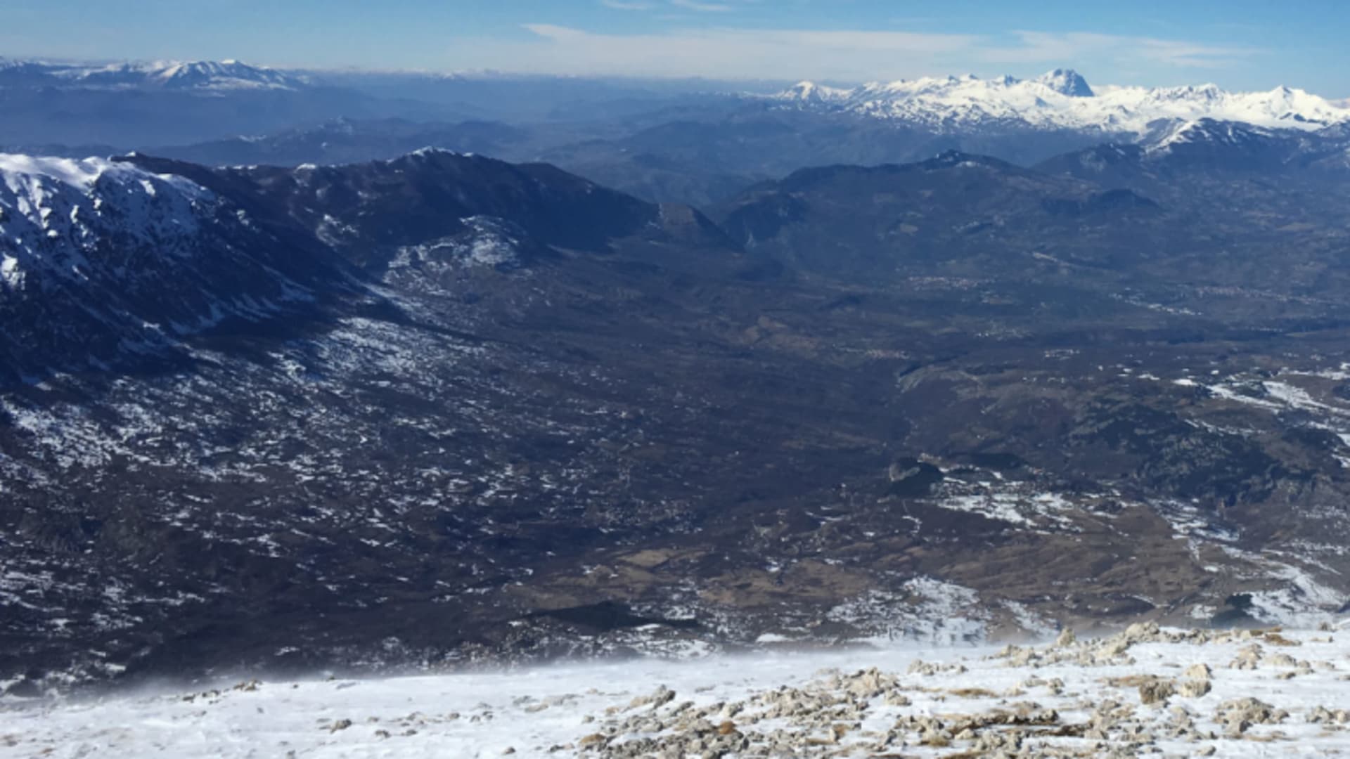 Skitour Gran Sasso Abruzzen: Panoramablick vom schneebedeckten Gipfelplateau über Felsblöcke, Tal