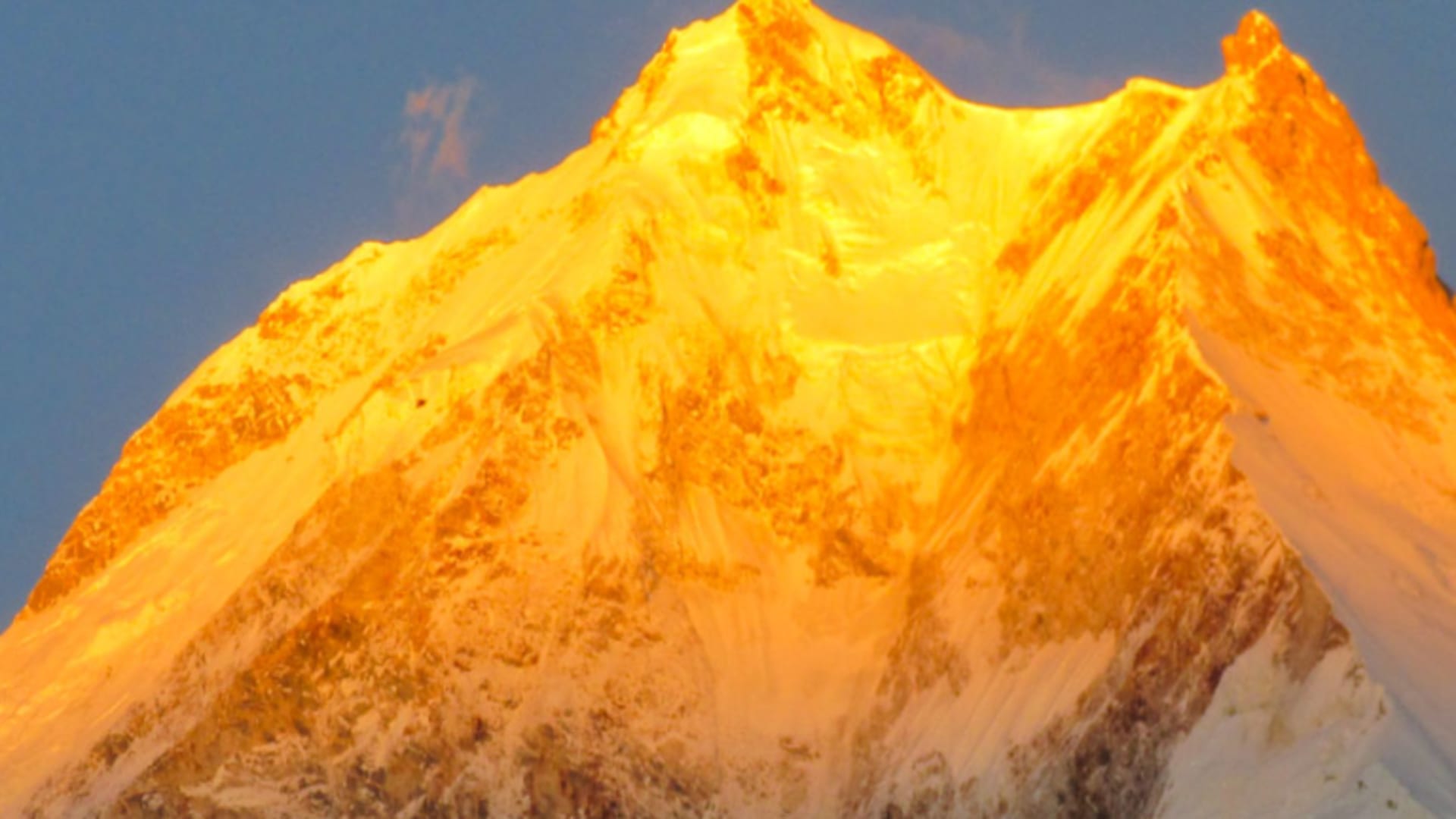 Trekking am Manaslu: pyramidenförmiger Achttausender in orange-goldenem Abendlicht, Schnee- und Eisflanken