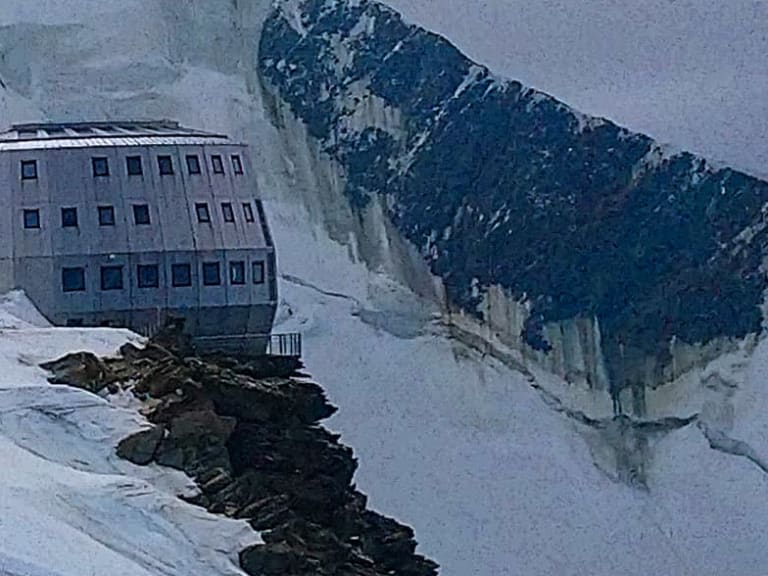 Das Refuge du Goûter steht als moderner Bau auf verschneitem Gletscherplateau im Mont-Blanc-Massiv.