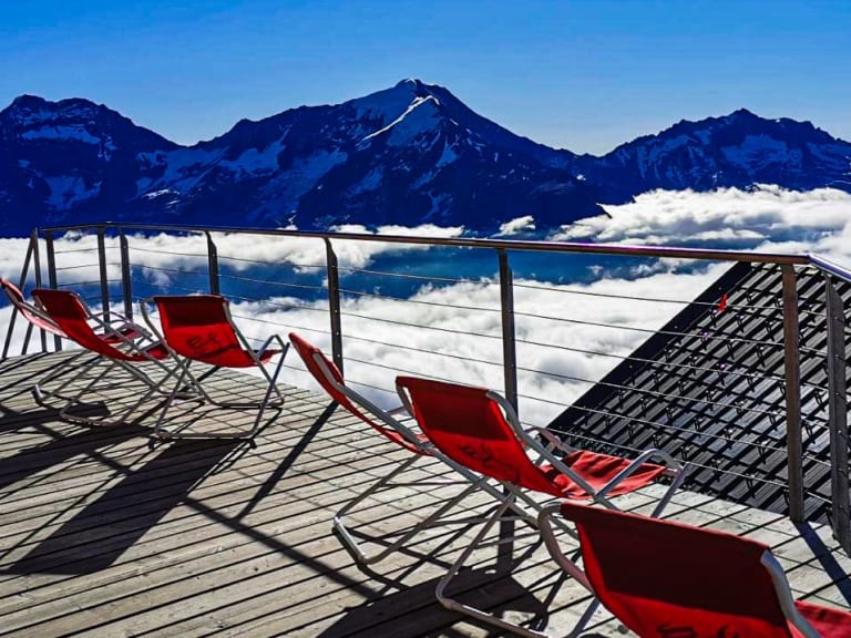 Blick von der Terrasse der Mischabelhütte über eine geschlossene Wolkendecke zu schneebedeckten Berggipfeln.