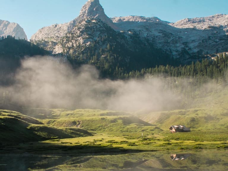 Panoramablick über den Funtensee mit dem Kärlingerhaus und pyramidenförmigem Felsgipfel in der Almlandschaft.
