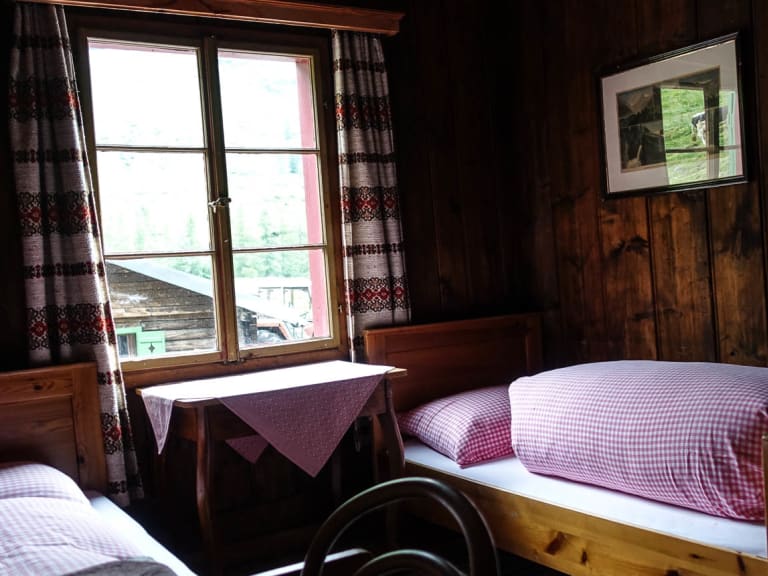 Komfortables Bergsteigerzimmer der Trauner Alm mit zwei Einzelbetten und rot-weiß karierter Bettwäsche.