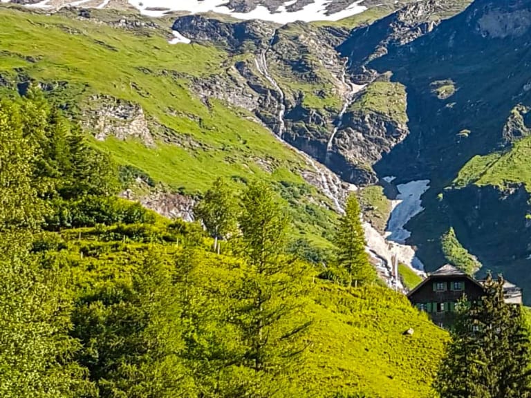 Panoramablick auf die Trauner Alm inmitten eines Alpentals mit schneebedeckten Bergen der Hohen Tauern.