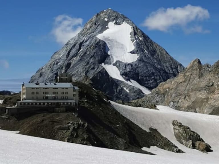 Fernblick zeigt das Rifugio Casati am Bildrand vor schneebedeckten Gipfeln und zusammenhängenden Gletscherflächen.