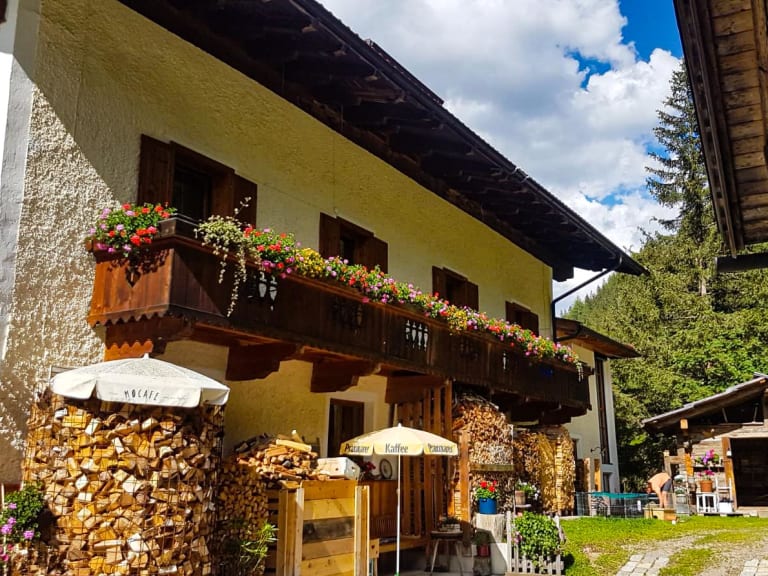 Gesamtansicht vom Alpengasthof Bad Kalkstein Innervillgraten mit gelbem Haupthaus und Sonnenschirmen.