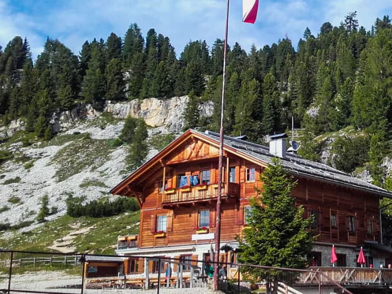 Außenansicht der Dürrensteinhütte mit rot-weiß-roter Fahne vor steiler Kalksteinwand der Dolomiten.