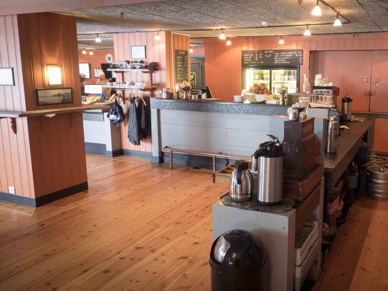 Gastraum mit grauem Tresen und Espressomaschine im Hotel Finse 1222 zeigt rustikale Holzvertäfelung.