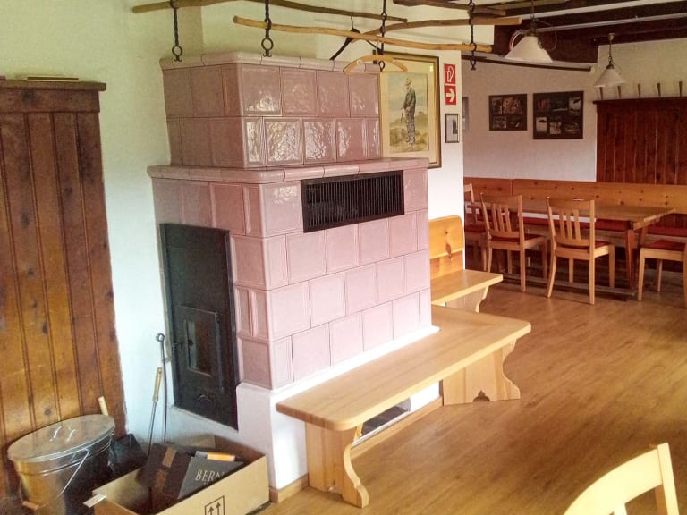 Gemütlicher Gastraum in der Traunsteiner Hütte mit traditionellem Kachelofen und Holzeinrichtung.