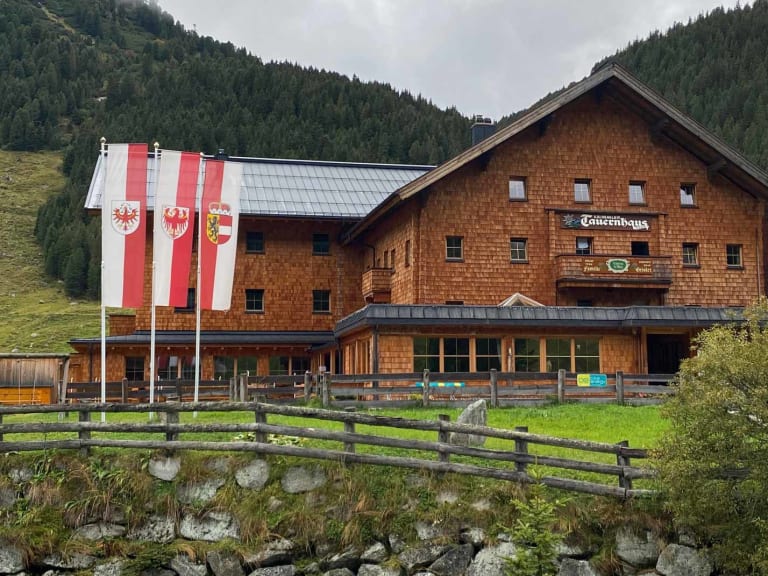 Außenansicht des Krimmler Tauernhauses mit Holzschindelfassade und überdachter Terrasse.