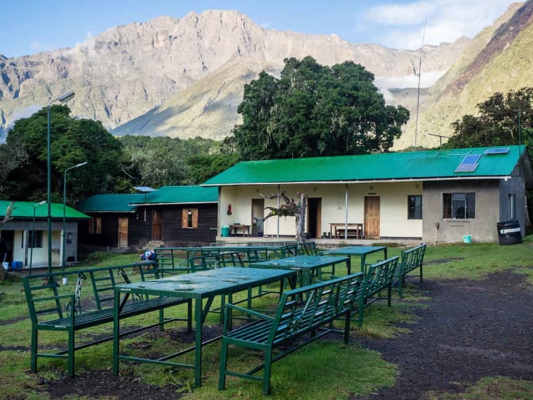 Die Miriakamba Hütte zeigt ihre grünen Gebäude und Außenterrasse umgeben von Bergwald am Mount Meru.