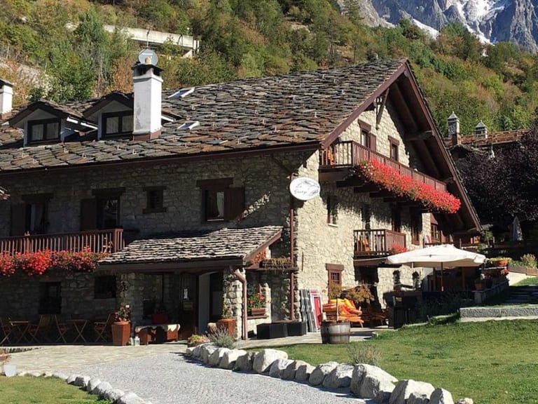 Das Hotel la Grange steht inmitten traditioneller Steinhäuser in Entrèves mit Mont-Blanc-Massiv im Hintergrund.