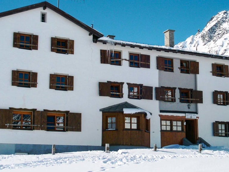 Die Heidelberger Hütte steht verschneit inmitten der winterlichen Silvretta-Bergwelt auf 2.264 m Höhe.