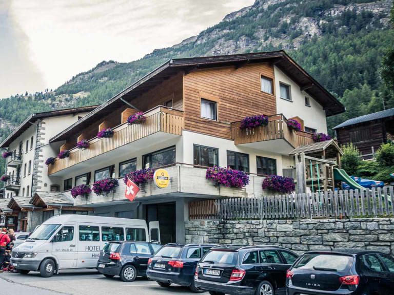 Außenansicht des Hotel Bergfreund in Herbriggen mit typischer Alpenarchitektur und Hotelbus im Mattertal.