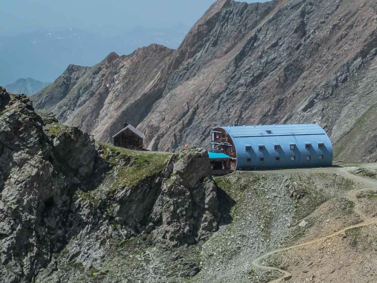 Panoramablick auf die moderne Stüdlhütte mit silbernem Blechdach auf felsigem Plateau in hochalpiner Lage.