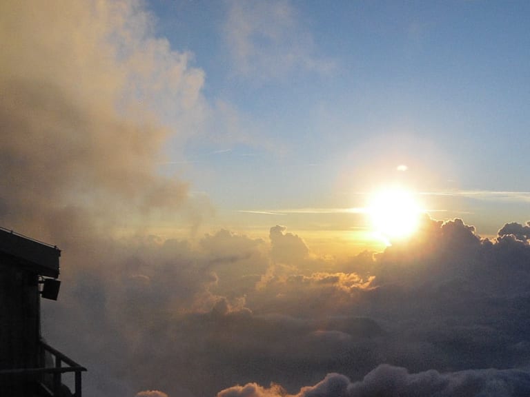 Sonnenaufgang an der Mittellegihütte mit goldenen Wolken über dem Tal der Berner Alpen.
