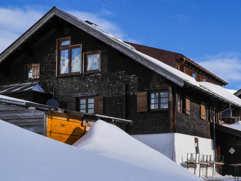 Die Schwarzwasserhütte steht tief verschneit auf 1.620 m in den winterlichen Allgäuer Alpen.