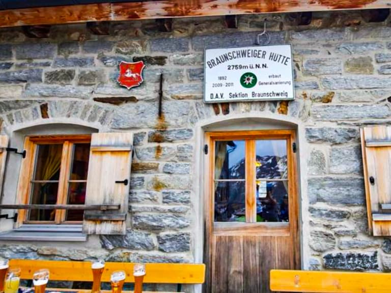 Frontalansicht der Braunschweiger Hütte aus Naturstein mit Hüttenschild und DAV-Logo in den Ötztaler Alpen.