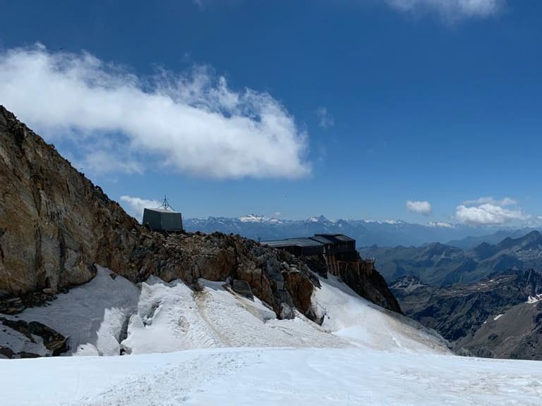 Panorama der Capanna Gnifetti auf schmalem Felsgrat zwischen Firn und Gletscherspalten.