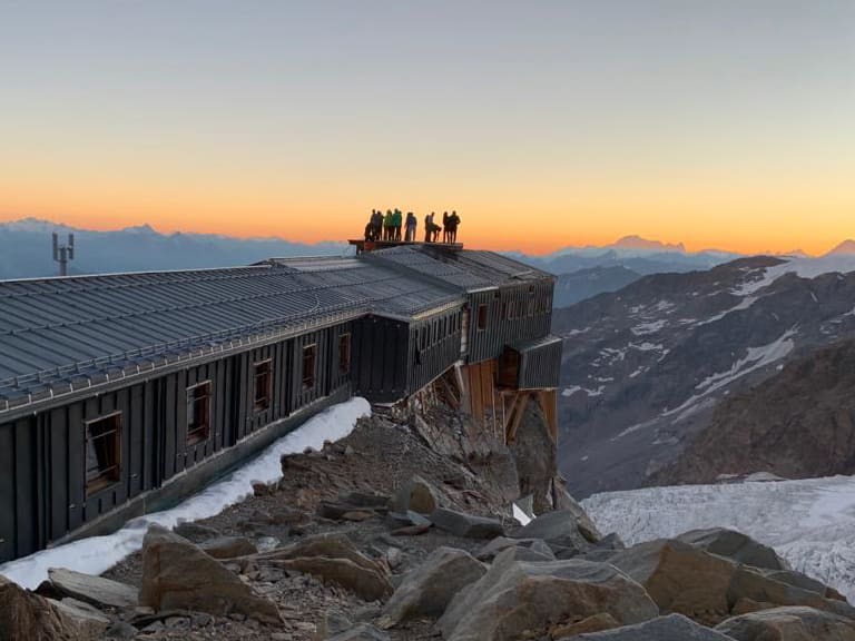 Bergsteiger auf dem Dach der Capanna Gnifetti bei Sonnenaufgang in den Walliser Alpen.