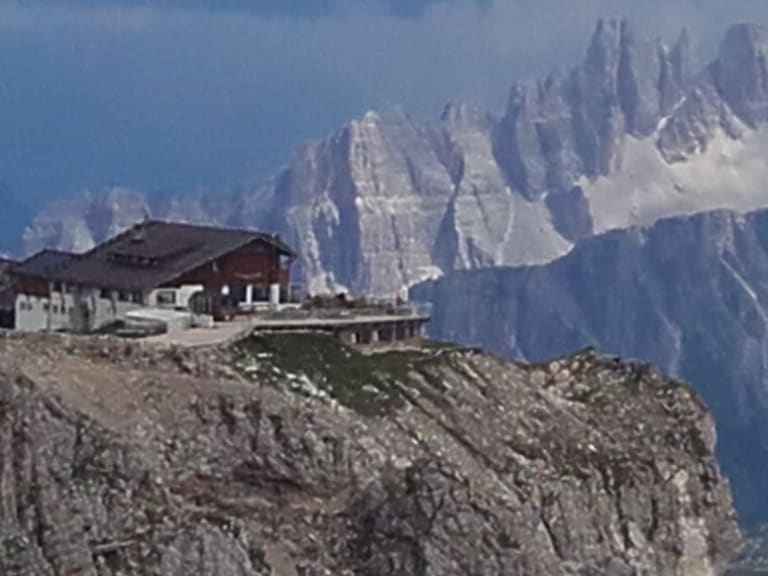 Das Rifugio Lagazuoi steht auf einem schmalen Dolomitfelsgrat mit steilen Gipfeln im Hintergrund.