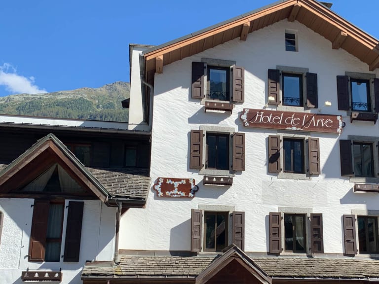 Hauptfassade des Hotel de L'Arve Chamonix mit weißer Fassade und braunen Holzfensterläden.