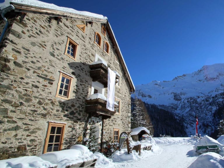 Der Ammererhof in Kolm-Saigurn zeigt sich im Winter als traditionelle Alpenherberge aus Naturstein mit schneebedeckter T