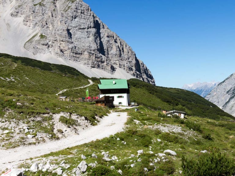 Panoramablick auf die Pfeishütte mit grünem Dach inmitten der Karwendel Kalksteinwände.