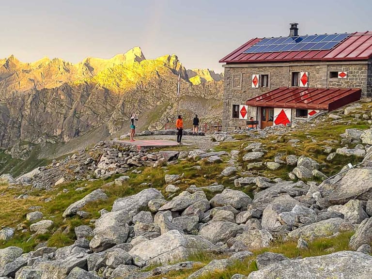 Bergwanderer mit Rucksäcken durchqueren ein Blockfeld vor dem Rifugio Gianetti auf 2.534 m in den Bernina-Alpen.