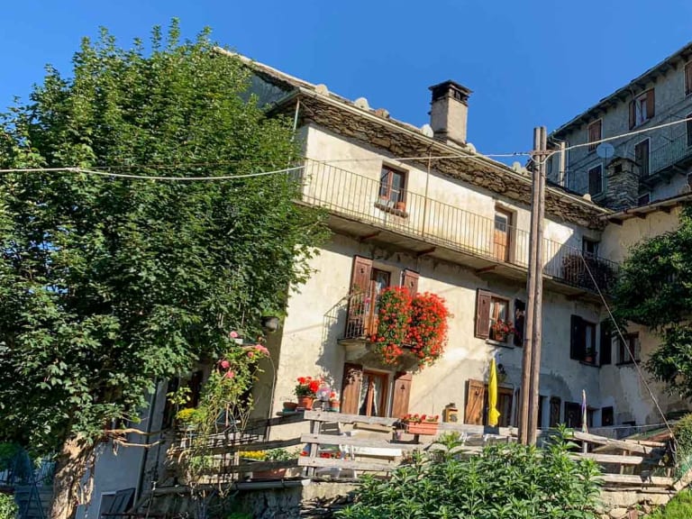 Außenansicht des Albergo Fontana mit traditioneller Walser Architektur und sonniger Terrasse in Rimella.