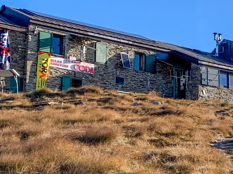 Das Rifugio Delfo e Agostino Coda liegt auf einem Hügel mit goldfarbenem Gras in den Walliser Alpen auf 2.280 m Höhe.