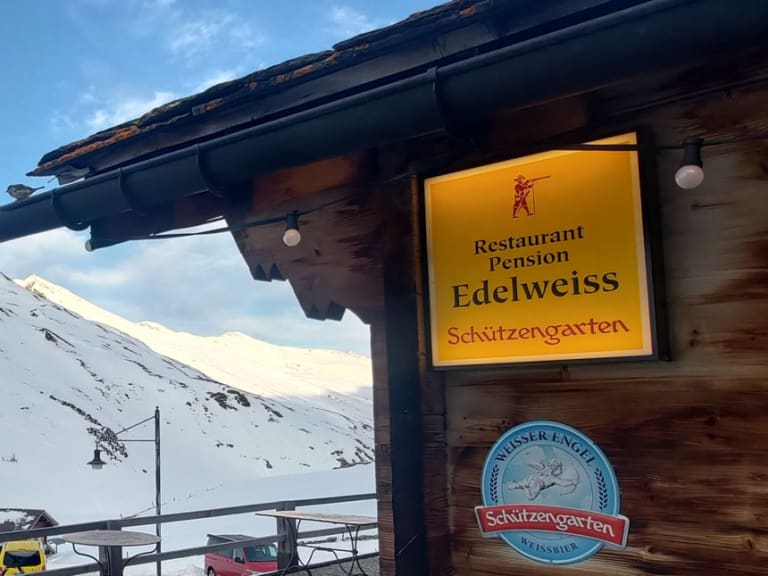 Die Pension Edelweiss Juf mit Holzfassade und Restaurant-Schildern steht verschneit auf 2.126 m Höhe im Averstal.