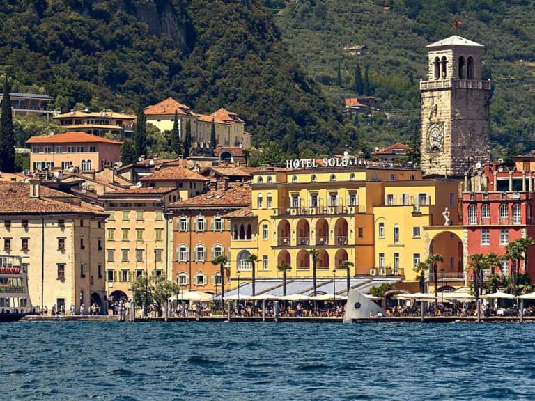 Bunte Hotelfront der Garda Hotels Riva **** direkt am türkisblauen Gardasee mit mediterraner Architektur.