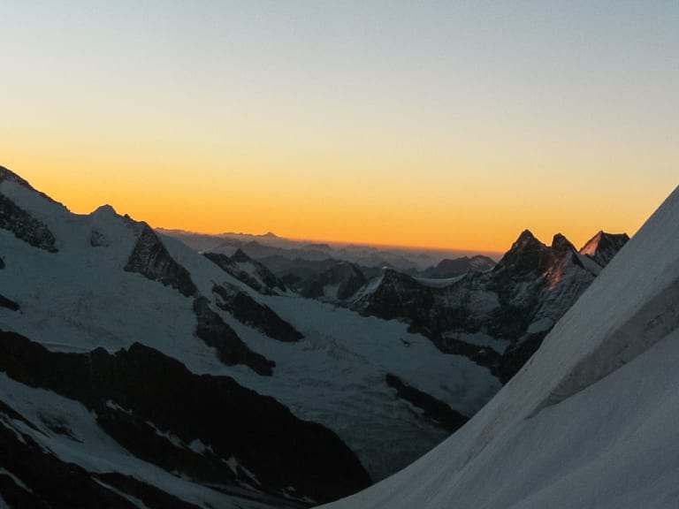 Bergsteiger-Seilschaft steigt bei Sonnenaufgang durch Gletscherhänge nahe der Mönchsjochhütte in den Berner Alpen auf.