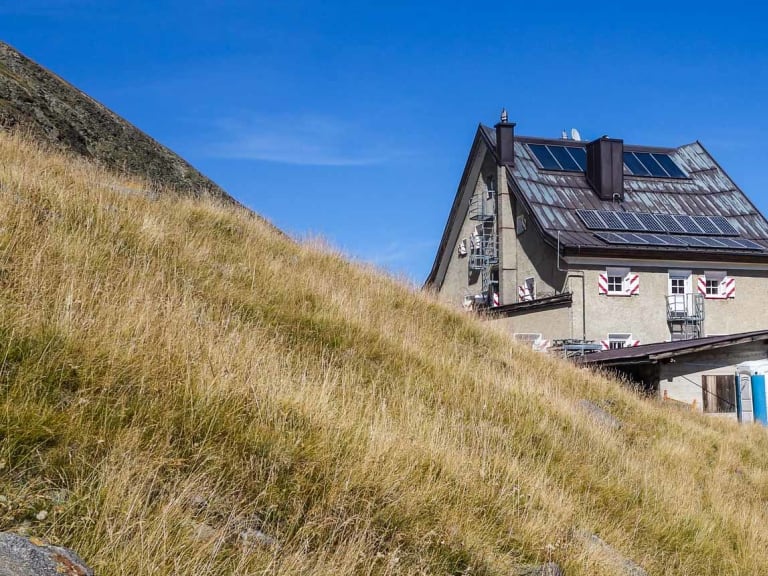 Das Hochjoch Hospiz liegt in steiler Hanglage zwischen hohen Bergen mit Solarpaneelen auf dem Dach.