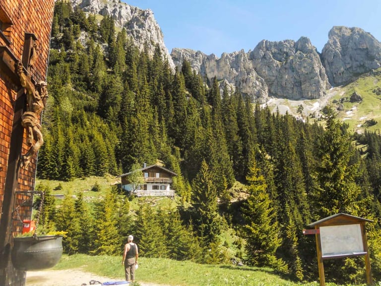 Bergwanderer auf der Terrasse vom Gimpelhaus mit Blick auf bewaldete Hänge und Kalksteinwände im Tannheimer Tal.