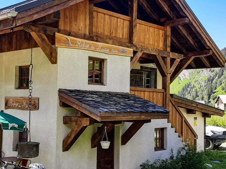 Das Refuge de Miage zeigt sich als traditionelle alpine Berghütte mit Holz-Stein-Konstruktion und Schieferdach.