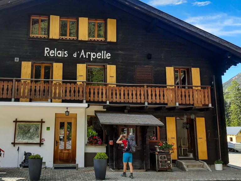 Das Relais d'Arpette zeigt sich als zweistöckige Berghütte mit dunkler Holzfassade und gelben Fensterläden am gepflaster