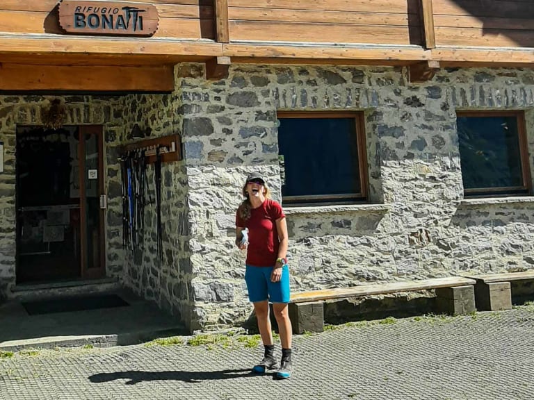 Außenansicht des Rifugio Alpino Walter Bonatti mit traditioneller Steinarchitektur und Wanderer vor dem Eingang.