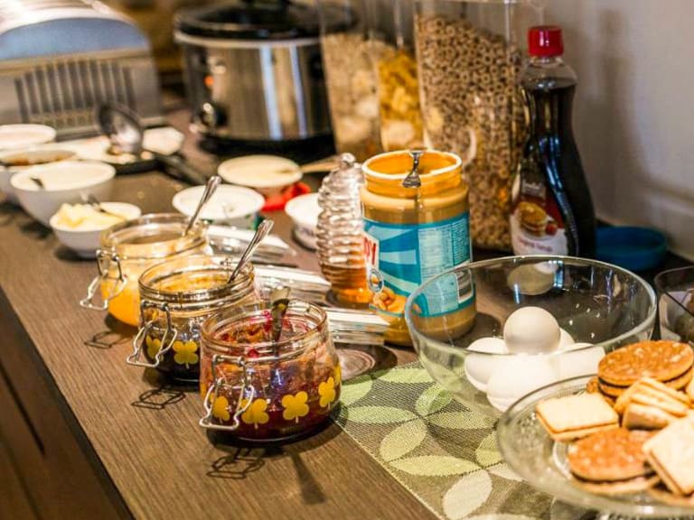 Frühstücksbuffet mit Käse, Marmelade, Eiern und Müsli im Hotel Duus by Keflavik Airport auf einem Holztisch arrangiert.