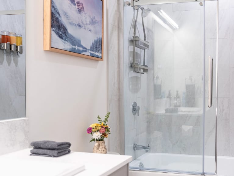 Badezimmer im Stoked Penthouse Revelstoke mit Badewanne-Dusch-Kombination und Marmoroptik-Fliesen.