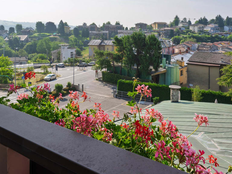 Vom Balkon des Hotel Pineta bietet sich Blick über Cerro Veronese mit Geranien im Vordergrund und bewaldeten Hügeln.