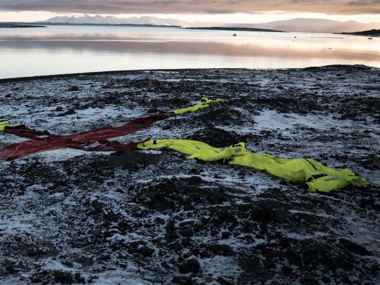 Rotes X-Kreuz mit neongelben Survival-Suits als Suchmarkierung an arktischer Küste im Winter.
