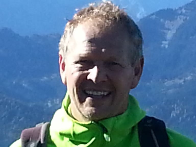 Lächelnder Bergwanderführer Martin Werner in grüner Outdoor-Jacke vor weiter Berglandschaft bei Garmisch.